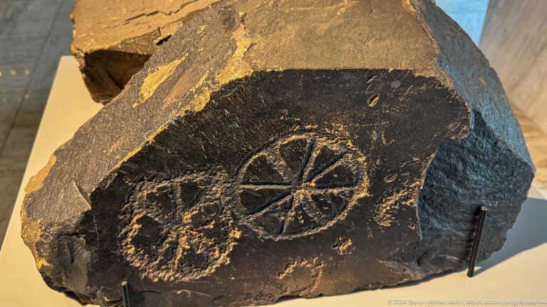 Dark stone slab carved with two spoked-wheel symbols.
