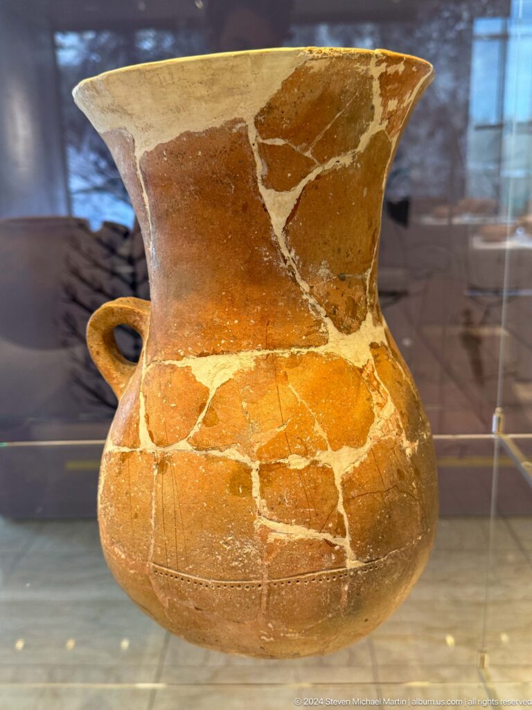 Reconstructed orange ceramic jug with one handle.