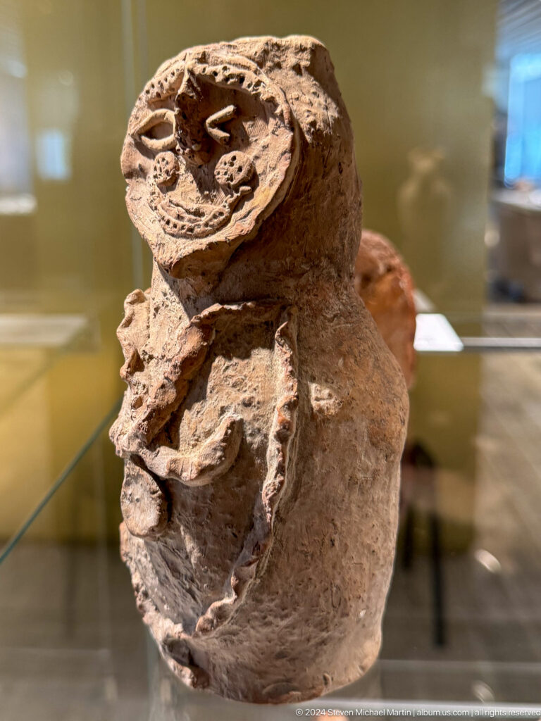 Fragmentary clay figure with projecting limbs.