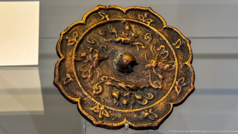 Round bronze mirror with scalloped rim and central boss.