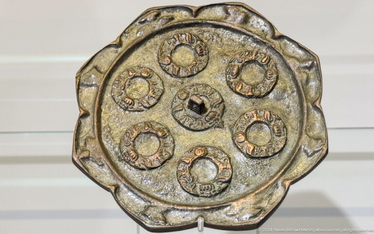 Round metal plate divided into small decorated medallions.