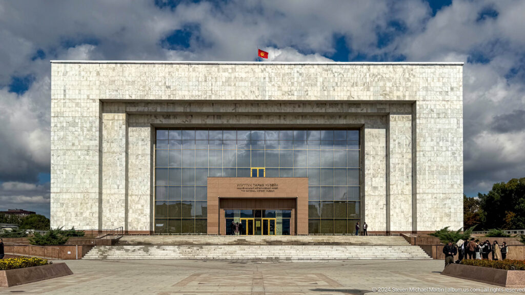 Symmetrical white-stone museum entrance with broad glass doors.