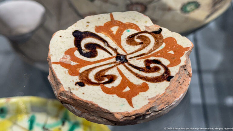 Round painted object with orange black and white floral design.