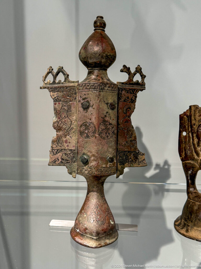 Ornate corroded metal box or fitting with projecting tabs.