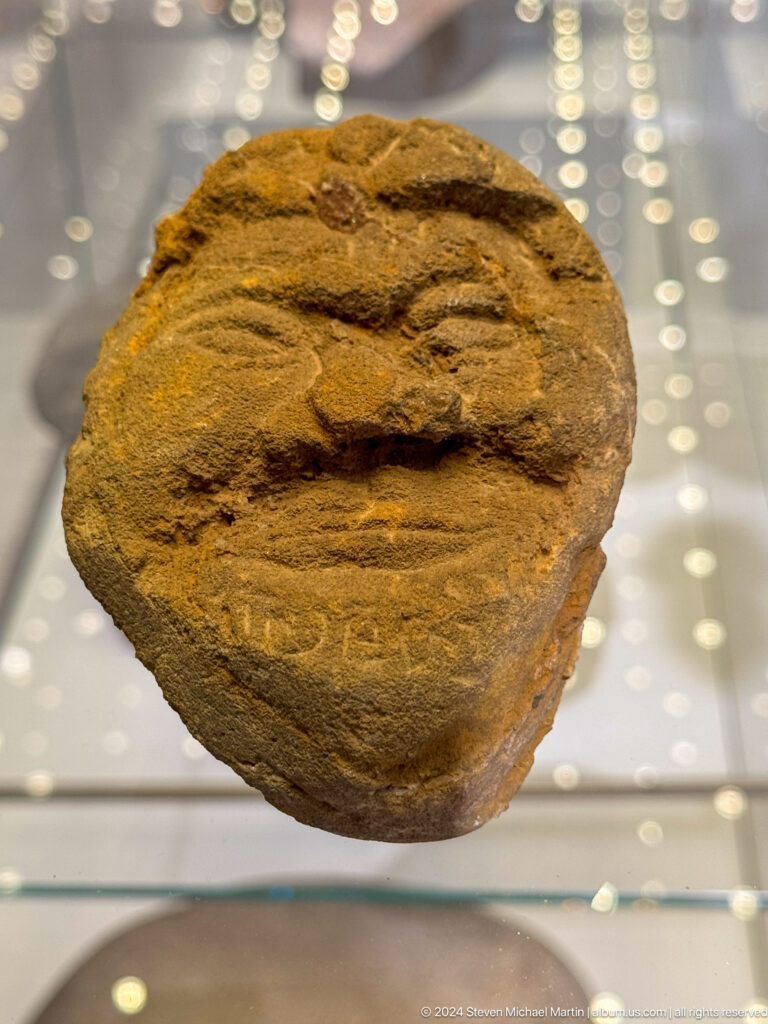 Small weathered stone face with broad lips.