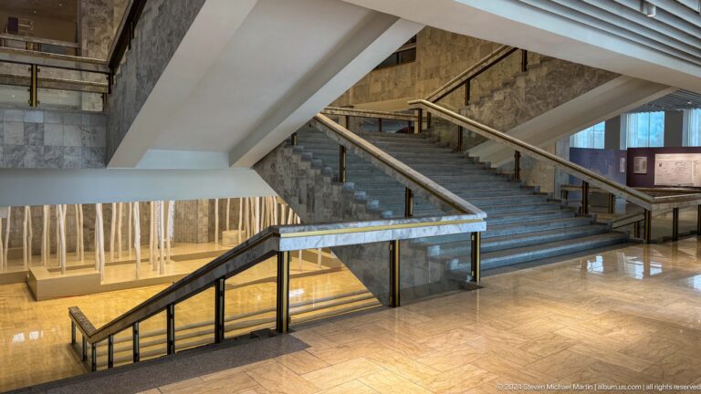 Broad museum staircase and ramp in a modern concrete hall.