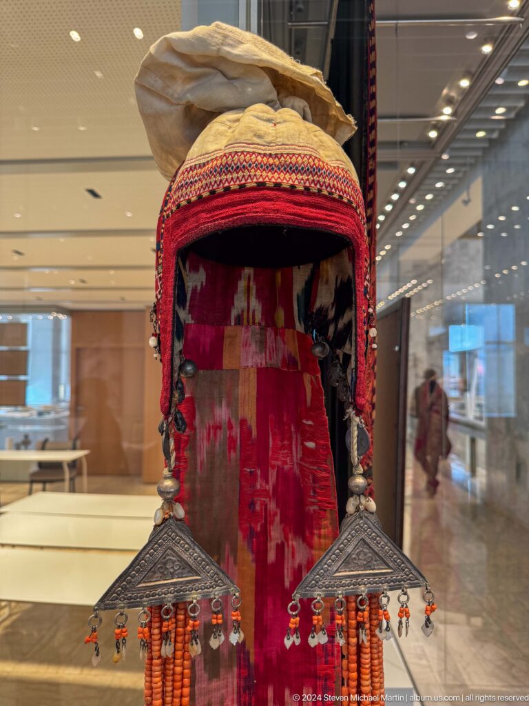 Red embroidered traditional garment displayed in a niche.