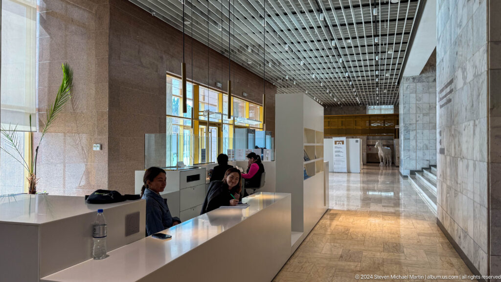 Modern museum reception desk beneath gridded ceiling.