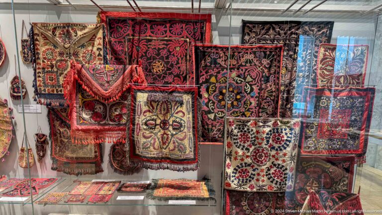 Wall of richly embroidered textiles and bags.
