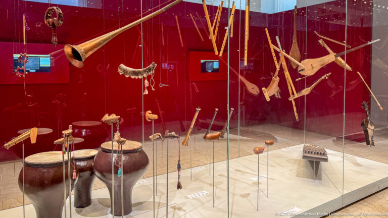 Glass case of bows arrows quivers and wooden weapons.