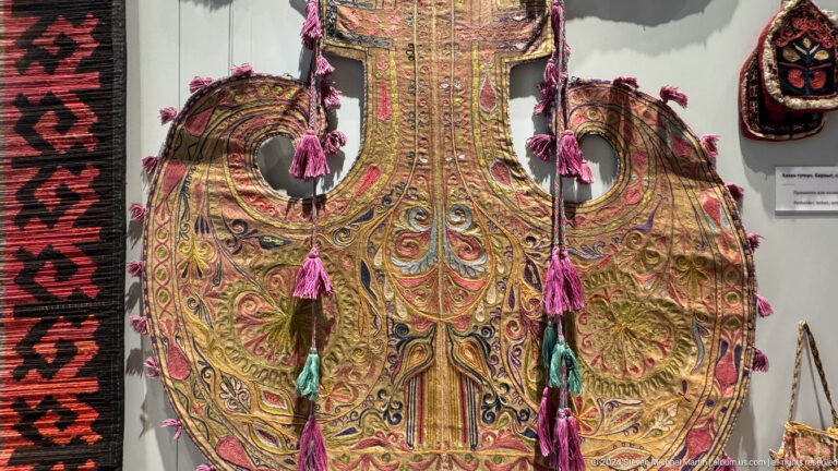 Ornate saddle textile with tassels and metallic embroidery.