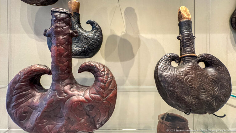 Two dark leather vessels with curved handles and necks.