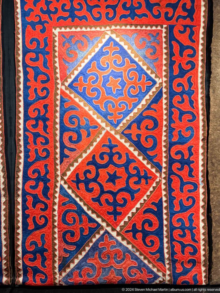 Red blue and orange felt carpet with central diamond.