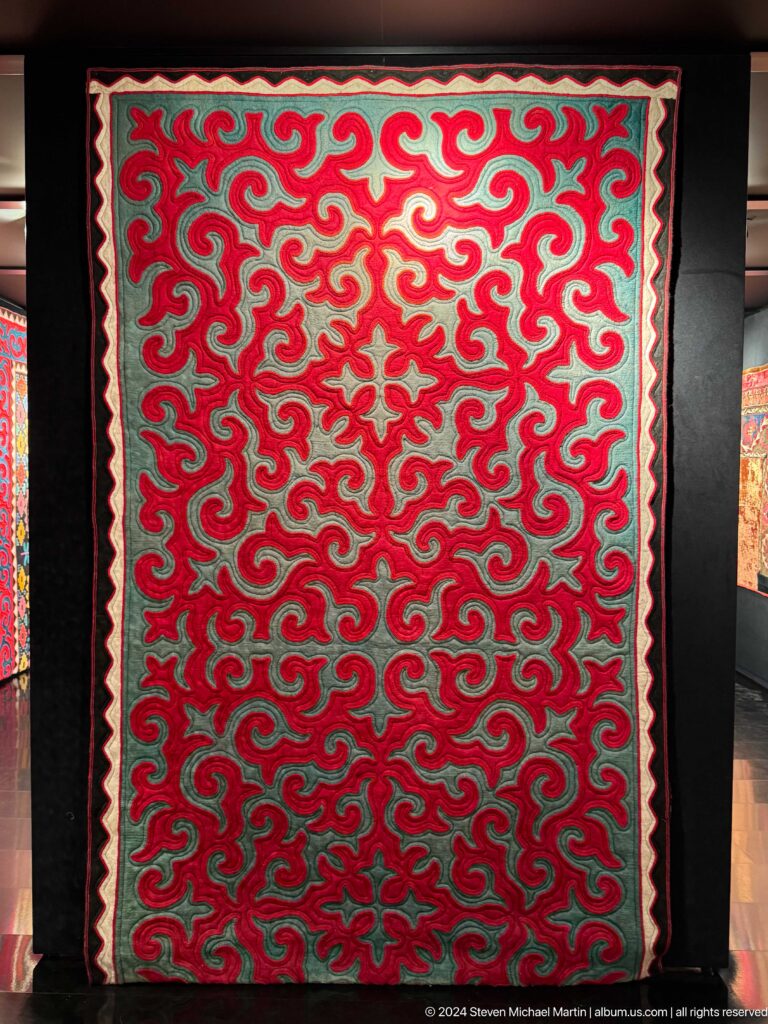 Red and green felt panel covered with curling motifs.