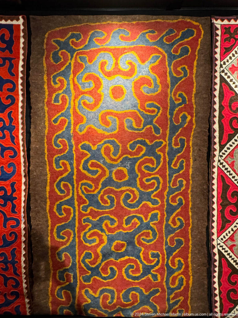 Orange blue and brown felt carpet with irregular scrolls.
