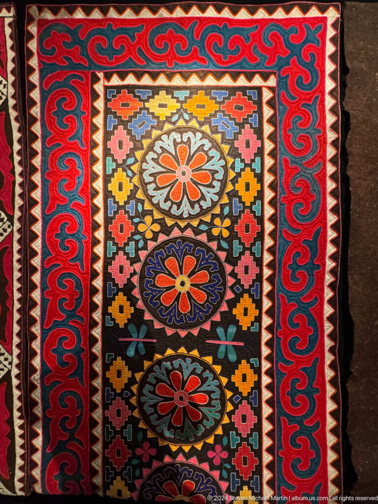 Black red and multicolored felt panel with floral medallions.