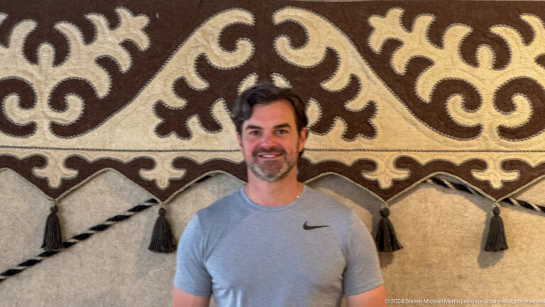 Smiling bearded male visitor against black and white felt ornament.