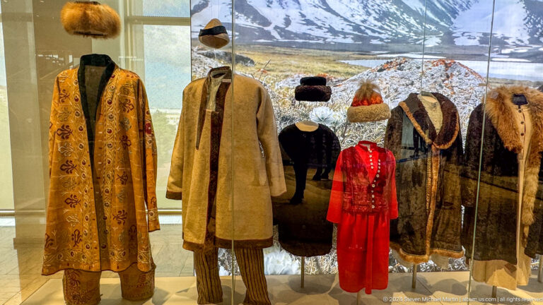 Row of traditional coats and hats in glass case.