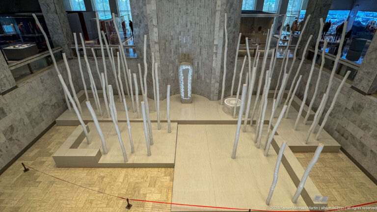 Abstract installation of many white vertical rods.