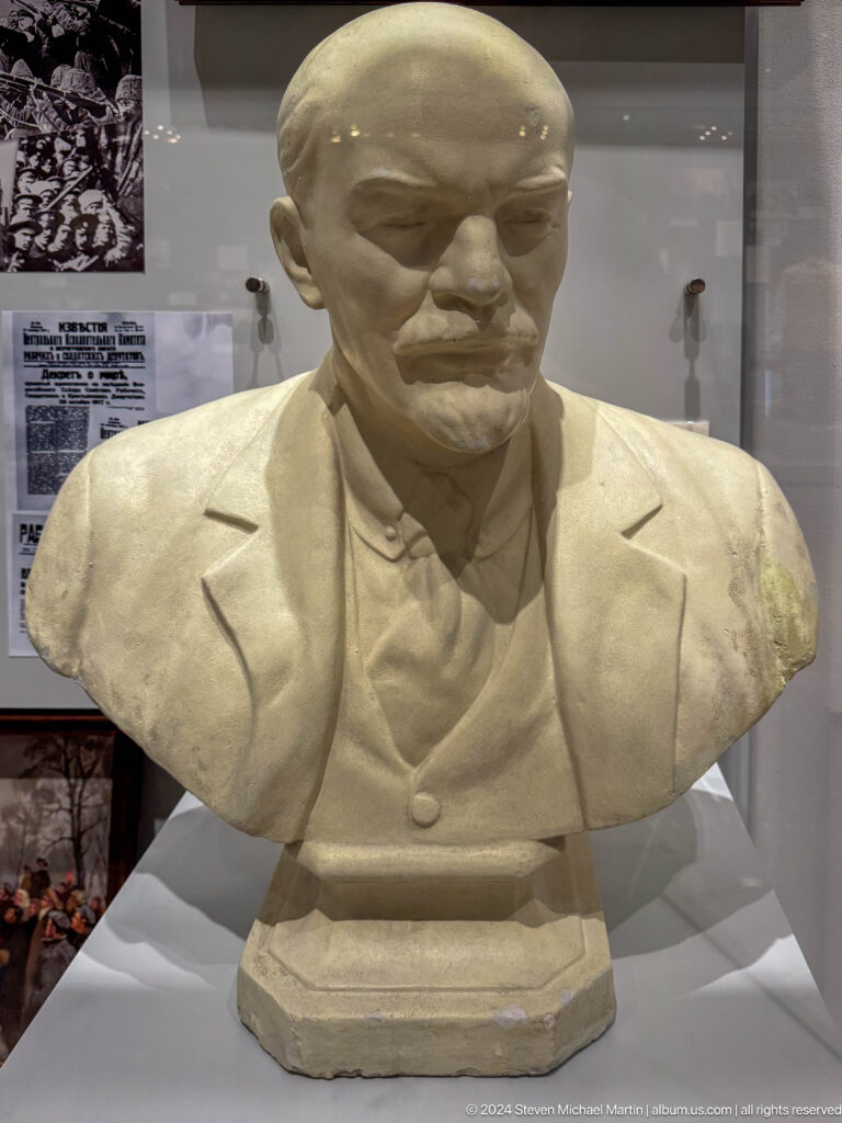 White sculpted bust of a mustached man in suit.