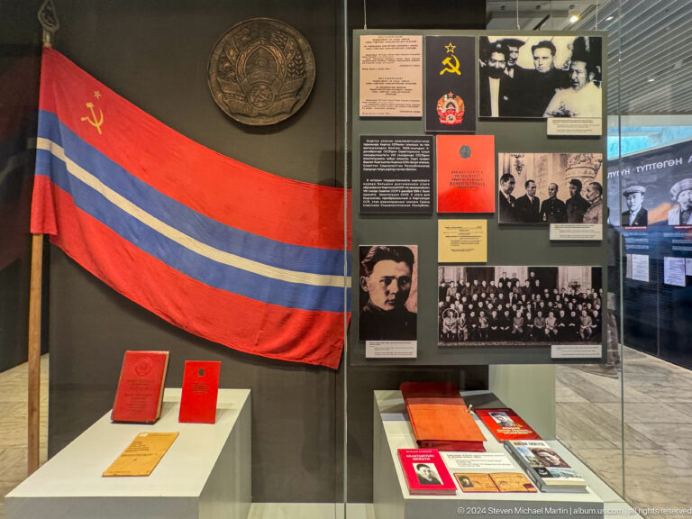 Soviet flag and memorabilia arranged on a black wall.