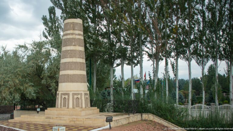A tall striped decorative tower stands within a landscaped roadside setting
