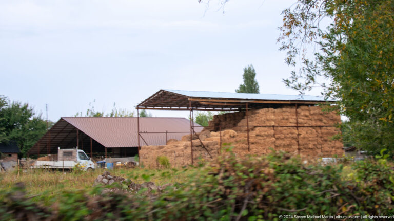 Earthen walls and farm structures stand beside fields on the approach to Burana