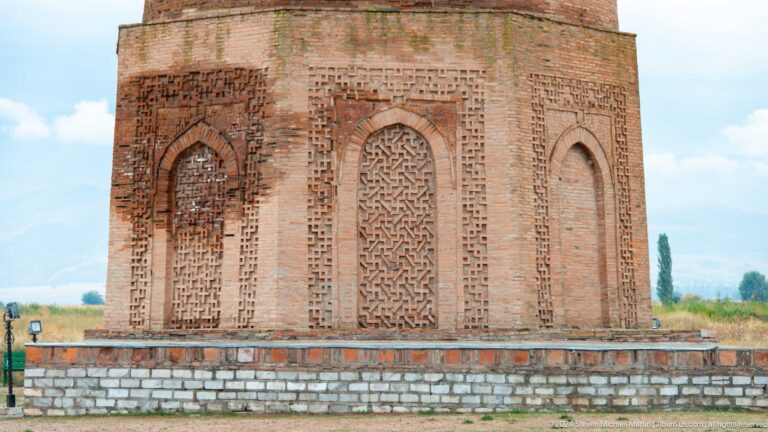 Blind arches and intricate brick patterns decorate the tower's square lower base