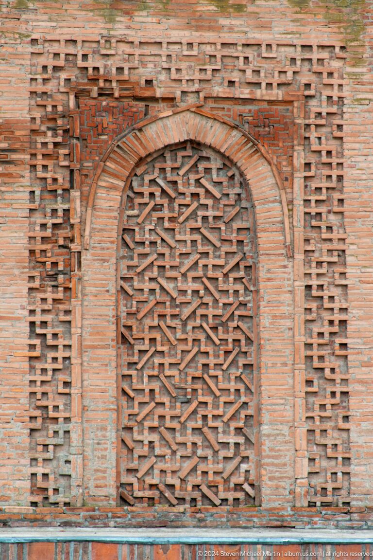 Interlocking geometric brickwork fills a tall recessed panel on the minaret