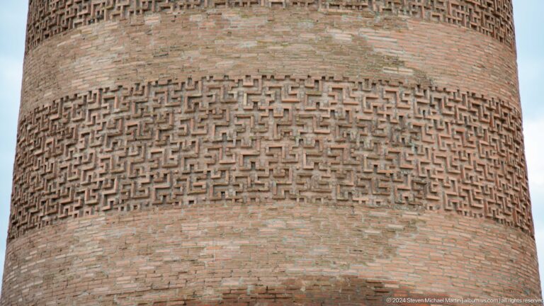 A dense repeating geometric pattern wraps around the tower's cylindrical shaft