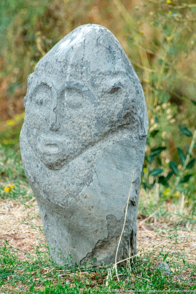 A small rounded stone preserves a simplified human face in shallow relief