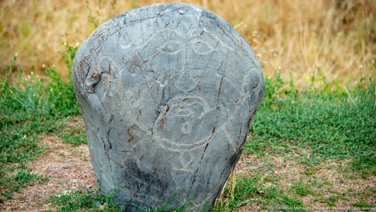 A dark irregular stone bears a weathered human figure carved in low relief