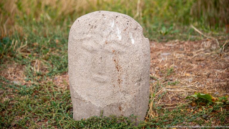 A compact upright stone displays a broad stylized face