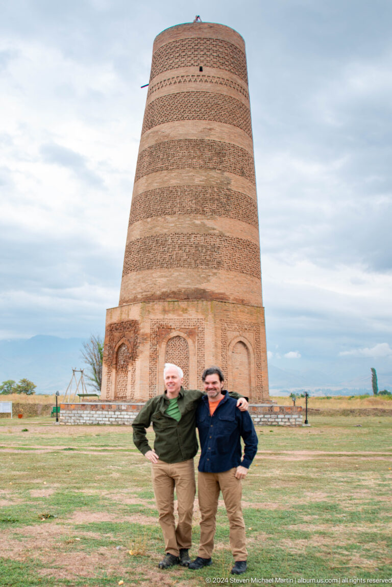 Two visitors are framed closely against the tower's lower section