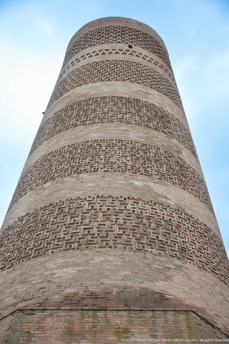 The camera looks steeply upward along alternating bands of patterned masonry