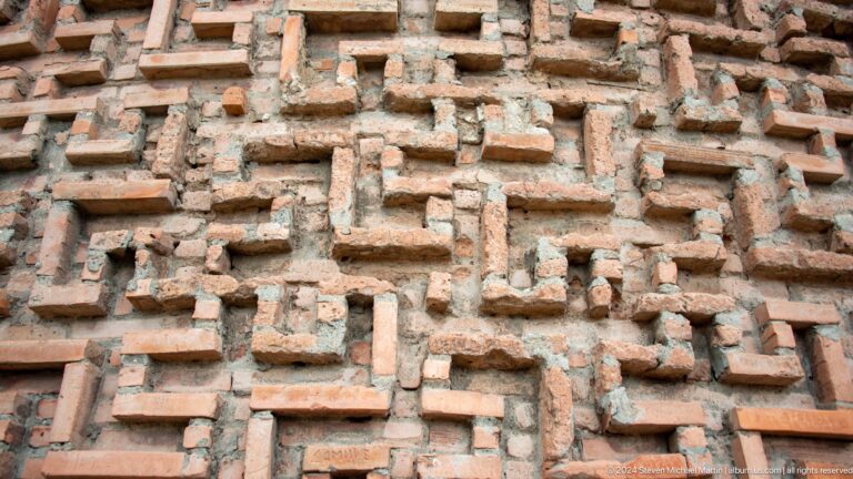 Projecting bricks form a maze-like ornamental pattern in weathered masonry