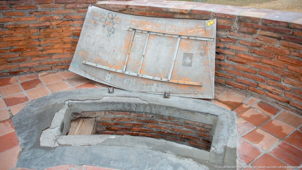An open metal-covered hatch provides access to the top platform