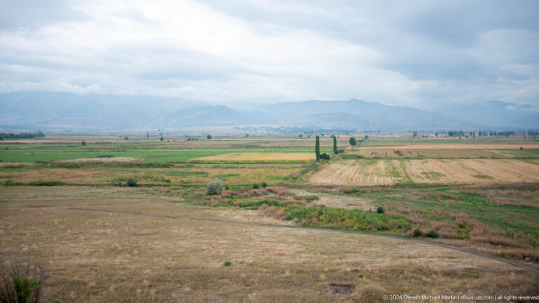 A broad agricultural plain stretches toward a hazy mountain range