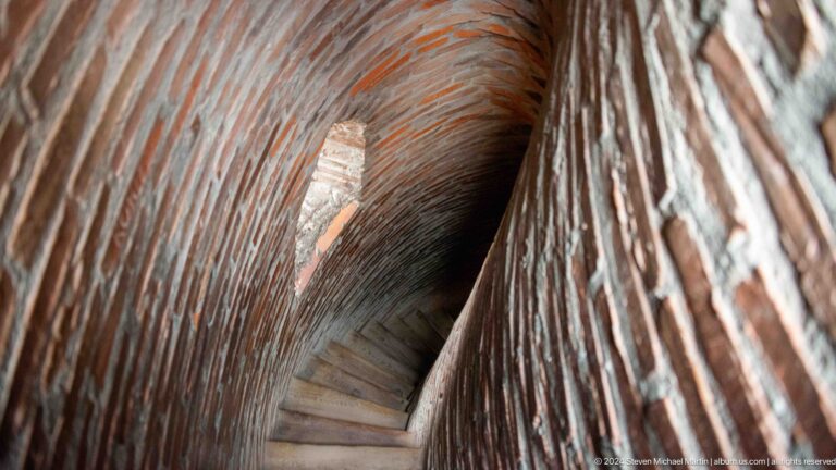 The camera looks down a confined brick stair passage inside the minaret