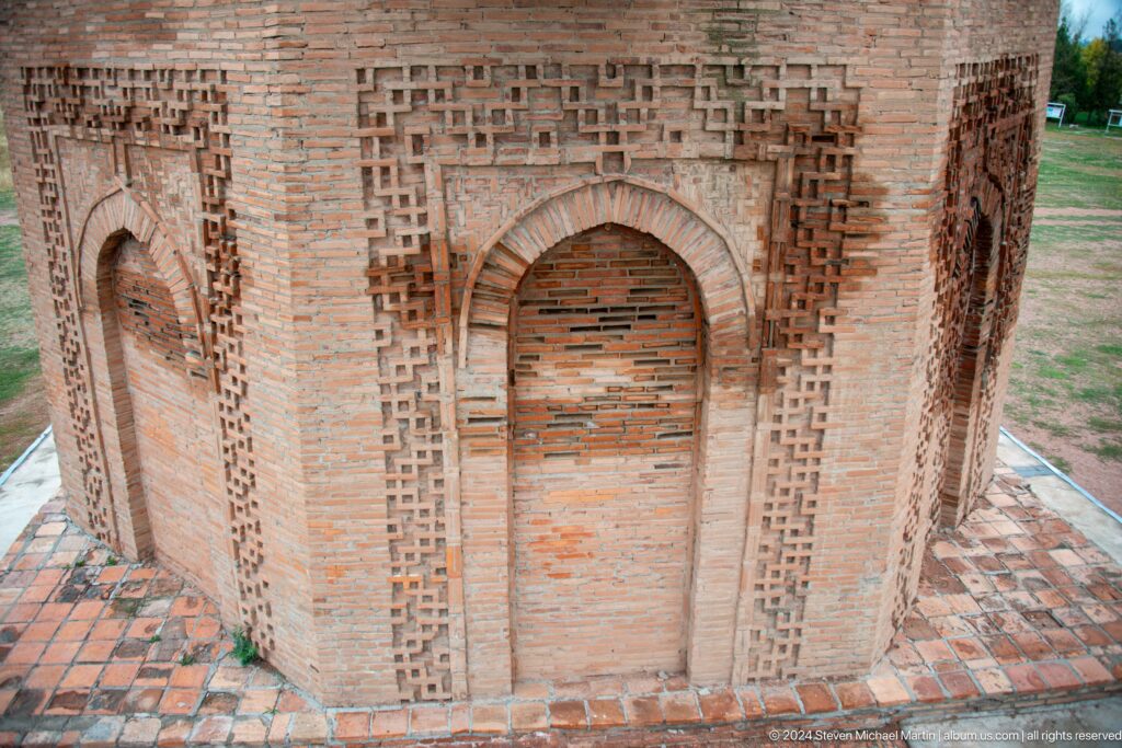 A tall blind arch is framed by intricate brick ornament on the lower façade