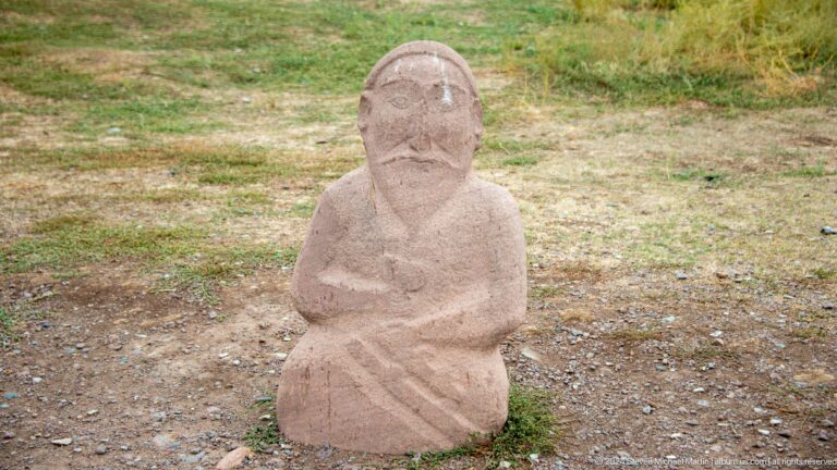 A compact carved stone figure sits with arms folded across the torso