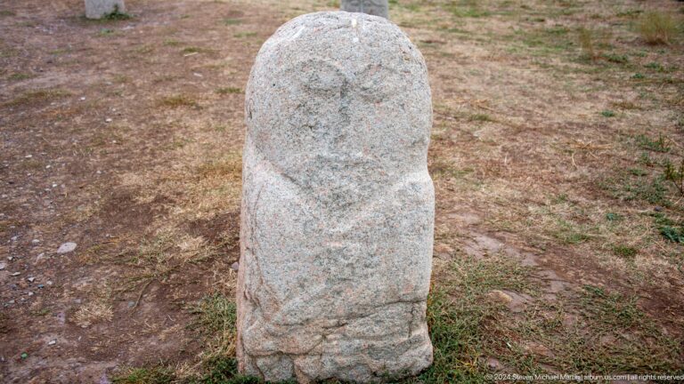 A narrow standing stone preserves a faint face and simplified body