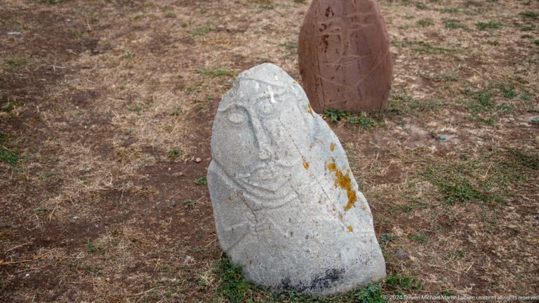 A pale rounded stone preserves facial features and linear carving