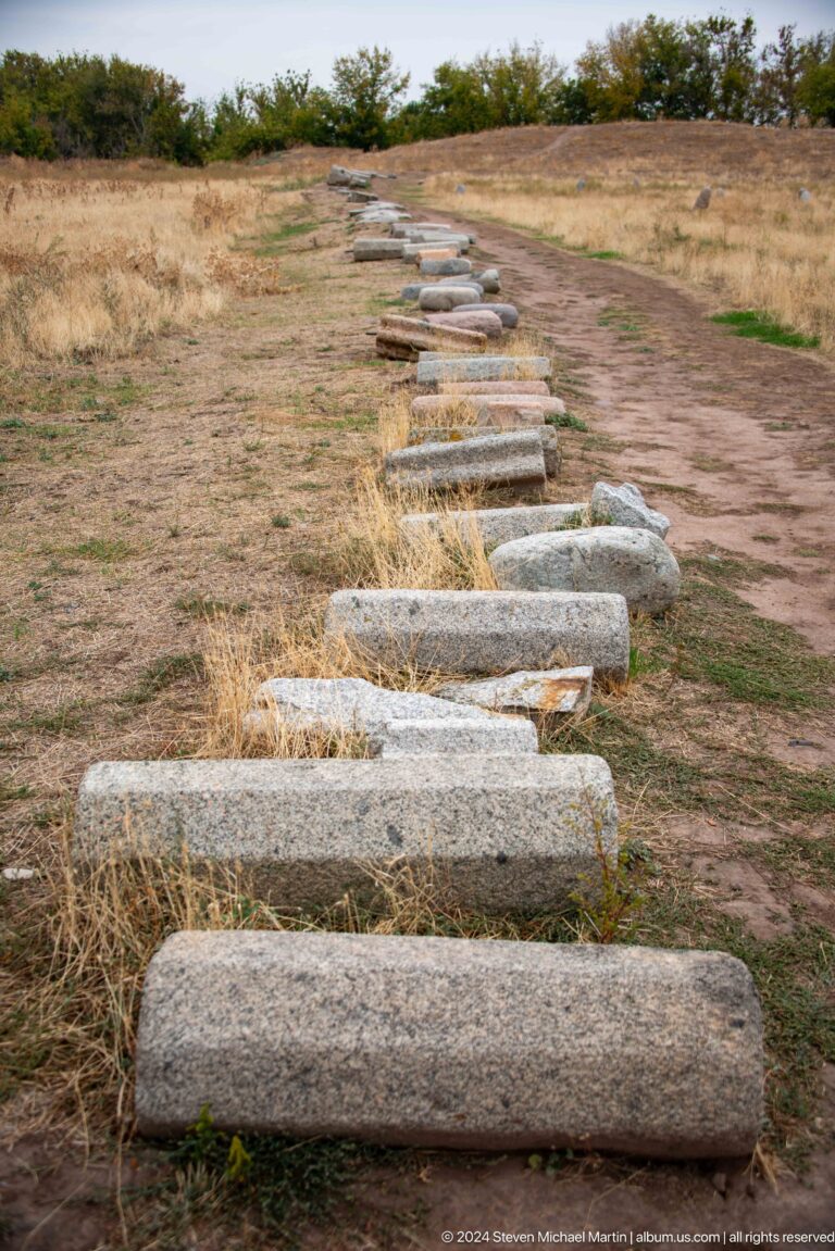 Long cylindrical stone fragments are arranged in rows on the ground