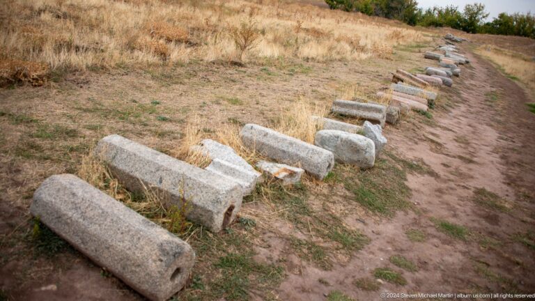 Numerous elongated stone pieces lie in an organized outdoor display