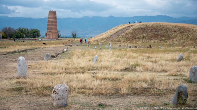 The tower, balbals, and a low archaeological mound occupy a broad open landscape