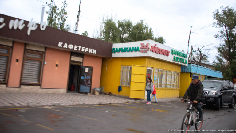 Colorful roadside shopfronts display Cyrillic signs for a cafeteria and bakery