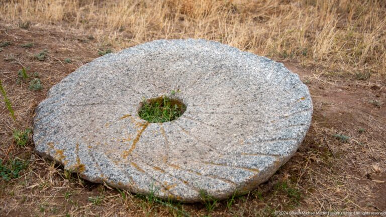 A thick circular stone with a central opening lies on the ground