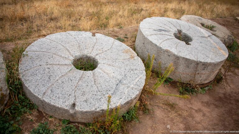Two circular grinding stones with central holes rest side by side
