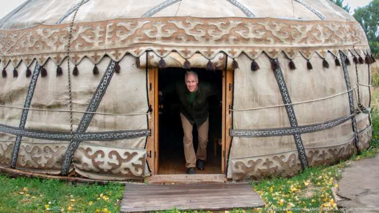 A visitor bends through the low doorway of a decorated yurt